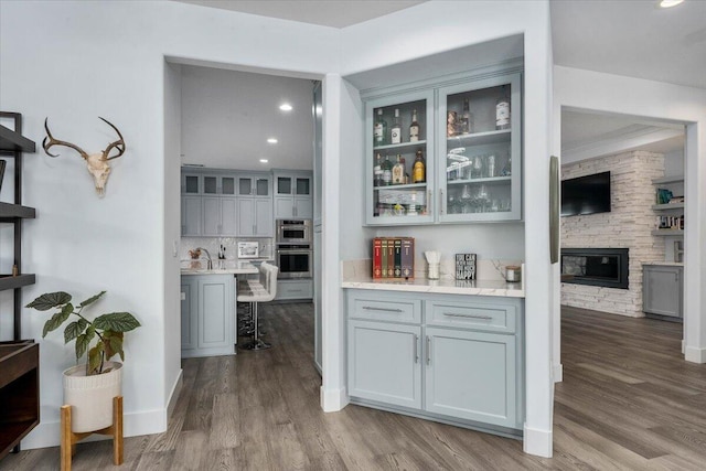 interior space with hardwood / wood-style flooring, a stone fireplace, gray cabinets, and backsplash