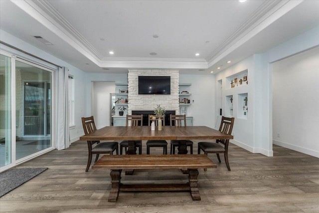 dining area with crown molding, hardwood / wood-style floors, and a tray ceiling