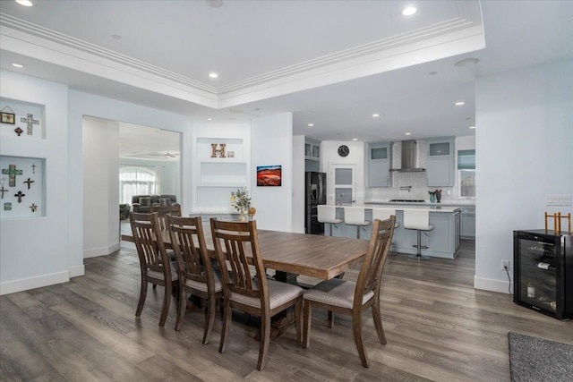 dining area featuring a raised ceiling, ornamental molding, wine cooler, and dark hardwood / wood-style flooring