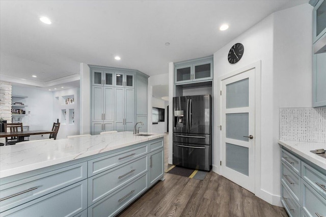 kitchen featuring sink, black refrigerator with ice dispenser, dark hardwood / wood-style floors, light stone countertops, and backsplash