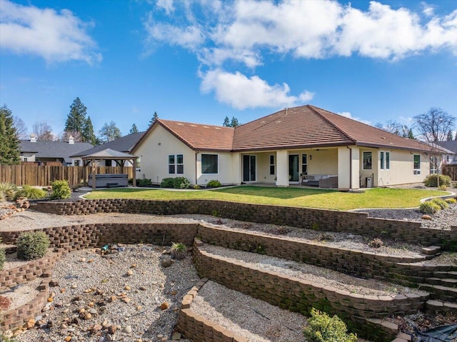 rear view of house featuring a yard, a gazebo, a hot tub, and a patio