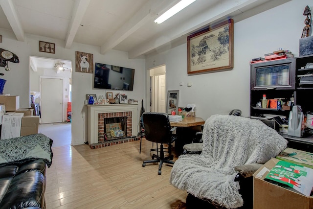 living room with a brick fireplace, beam ceiling, and light hardwood / wood-style floors