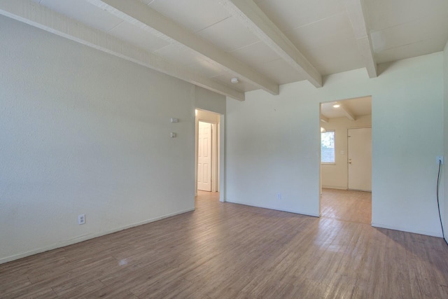 empty room with beam ceiling and hardwood / wood-style floors