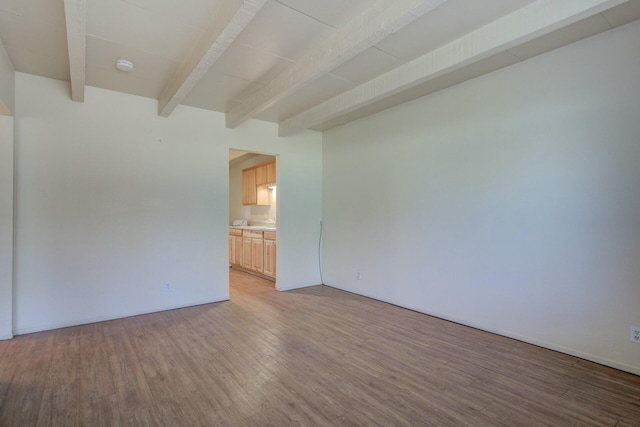 unfurnished room with beam ceiling and wood-type flooring