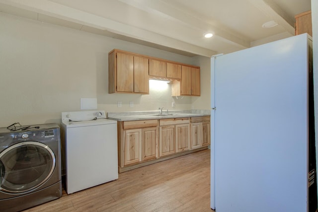 clothes washing area featuring sink, washer and dryer, and light wood-type flooring