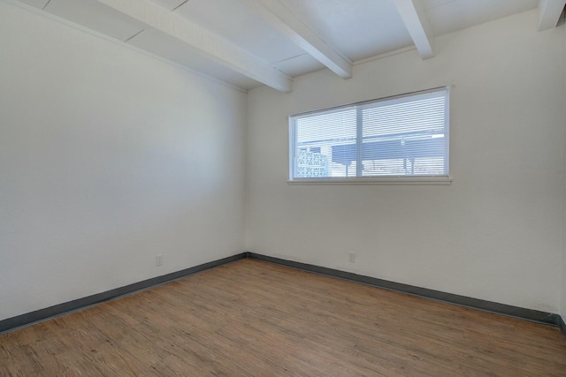 empty room with wood-type flooring and beam ceiling