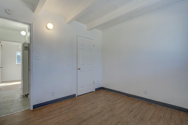 spare room with beamed ceiling and hardwood / wood-style flooring