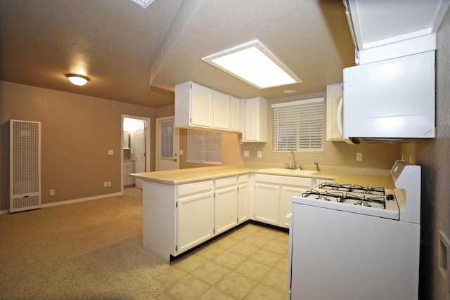 kitchen with white gas range, light colored carpet, sink, white cabinetry, and kitchen peninsula