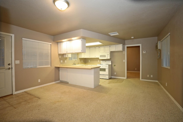 kitchen with white appliances, an AC wall unit, white cabinets, light colored carpet, and kitchen peninsula