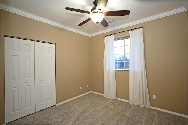 unfurnished bedroom featuring ceiling fan, ornamental molding, carpet floors, and a closet