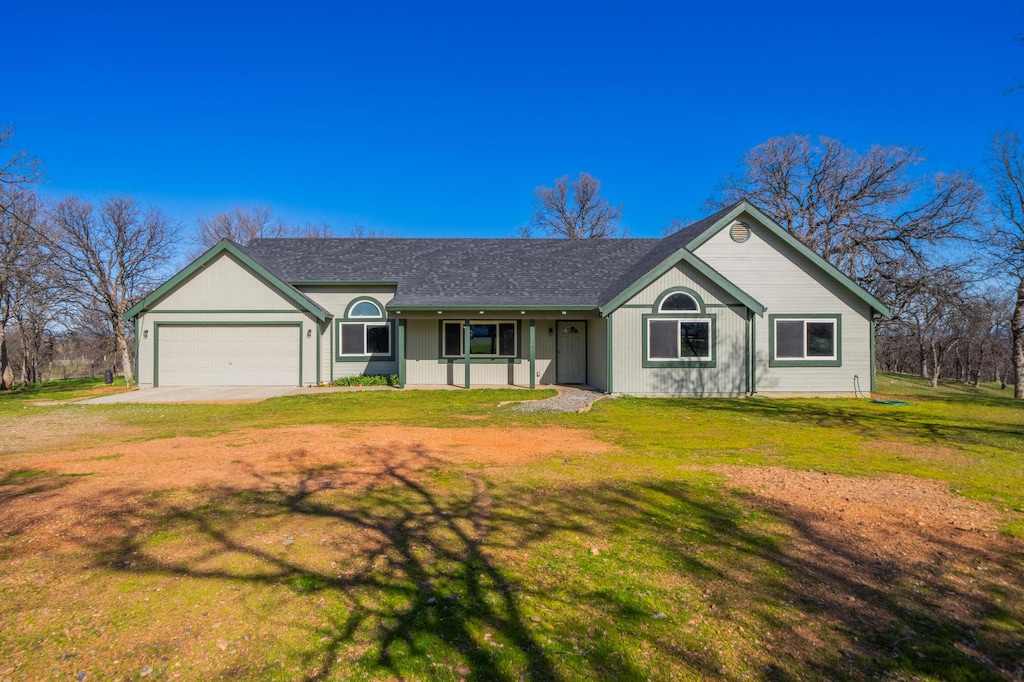 ranch-style home featuring a garage, covered porch, and a front lawn