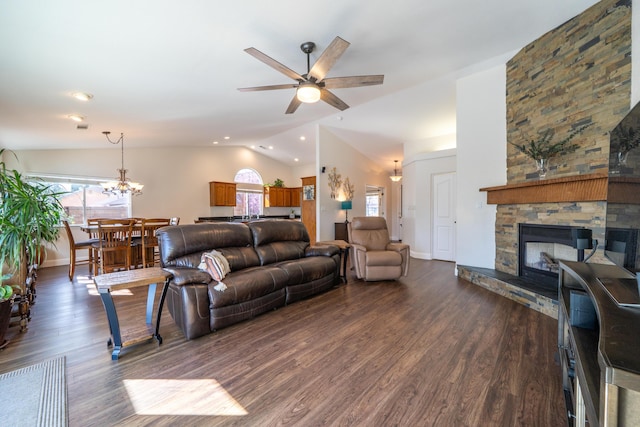 living room with lofted ceiling, ceiling fan with notable chandelier, dark wood-type flooring, a fireplace, and baseboards