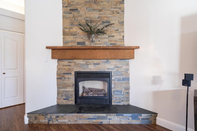 room details featuring a fireplace, baseboards, and wood finished floors