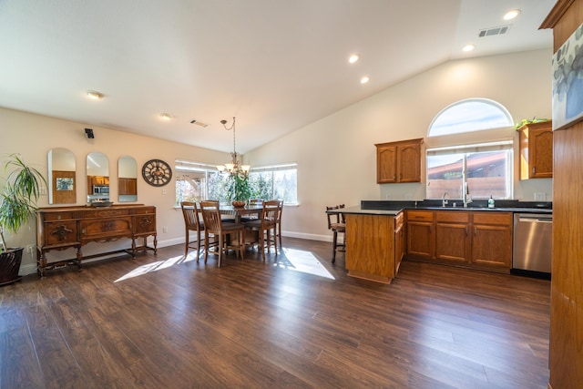 kitchen featuring dark wood-type flooring, appliances with stainless steel finishes, brown cabinetry, dark countertops, and pendant lighting