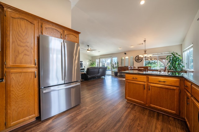 kitchen featuring dark countertops, brown cabinets, open floor plan, decorative light fixtures, and freestanding refrigerator