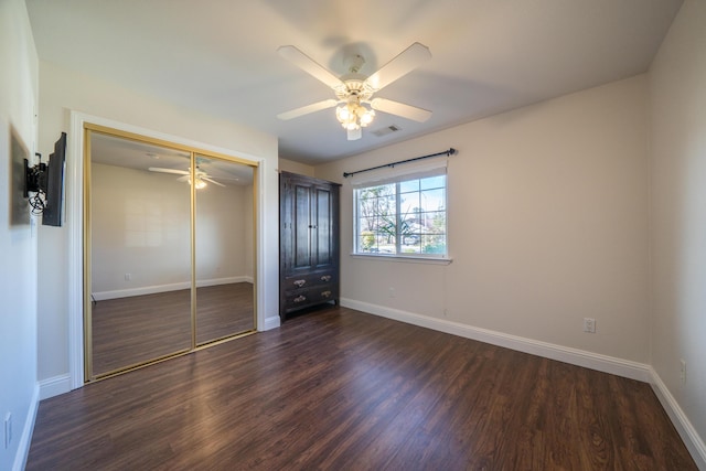 unfurnished bedroom featuring baseboards, a closet, visible vents, and dark wood-style flooring