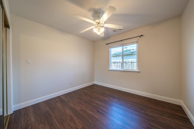 spare room with ceiling fan, dark wood-style flooring, and baseboards