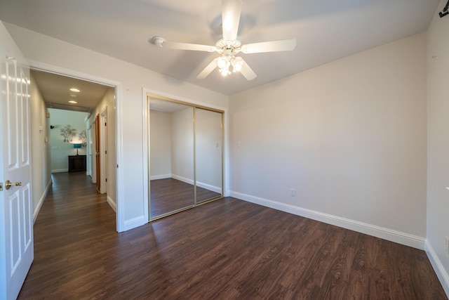 unfurnished bedroom with a closet, dark wood finished floors, and baseboards