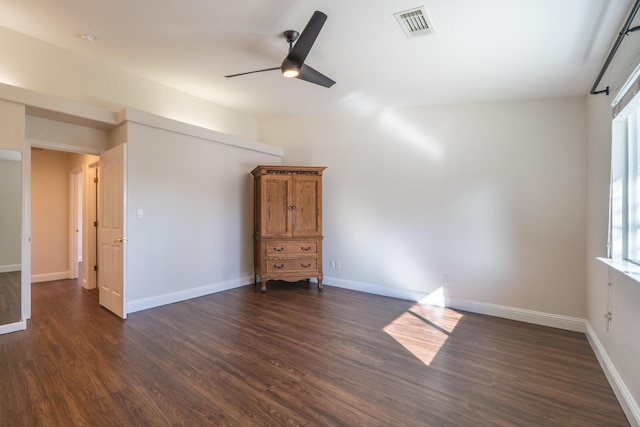 empty room with baseboards, visible vents, and dark wood-type flooring