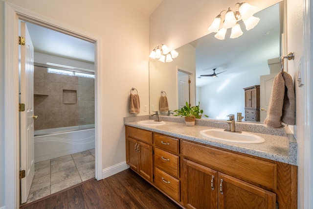 bathroom featuring wood finished floors, double vanity, combined bath / shower with glass door, and a sink