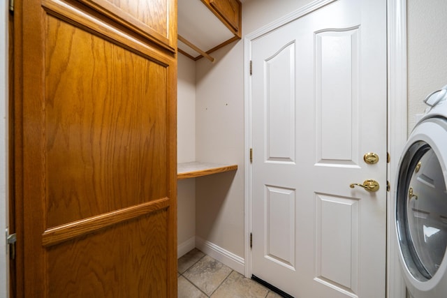 laundry area with laundry area, light tile patterned flooring, washer / dryer, and baseboards