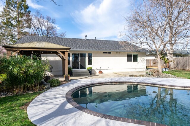 rear view of property with entry steps, fence, a gazebo, stucco siding, and a patio area