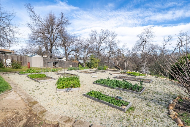 view of yard featuring a shed, fence, a vegetable garden, and an outdoor structure