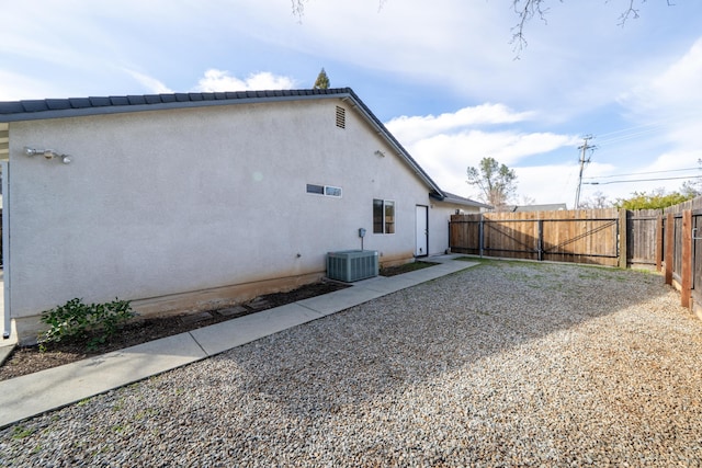 view of home's exterior featuring stucco siding, fence, and central air condition unit