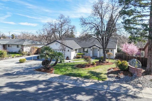 single story home with a garage, concrete driveway, a residential view, fence, and a front yard