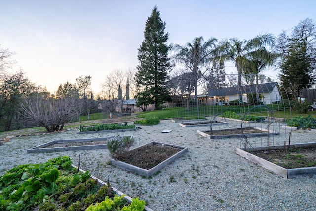 view of community featuring fence, a vegetable garden, and a lawn