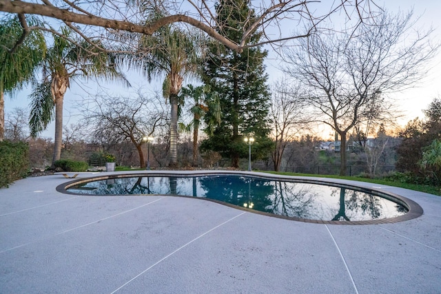 pool at dusk featuring a patio area and an outdoor pool