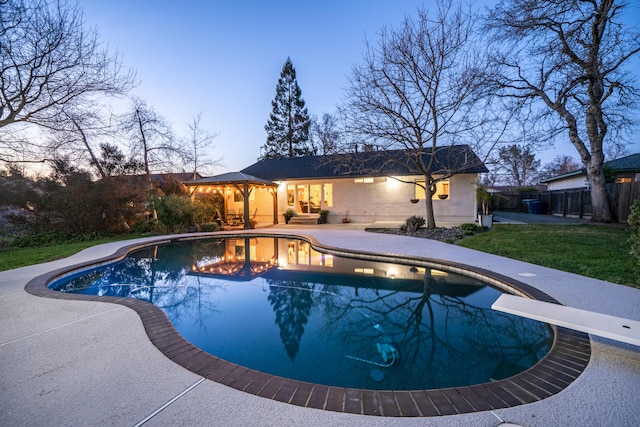 pool at dusk with a lawn, fence, a fenced in pool, and a patio