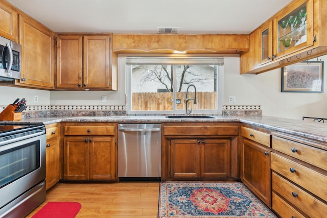 kitchen with stainless steel appliances, sink, and light hardwood / wood-style floors