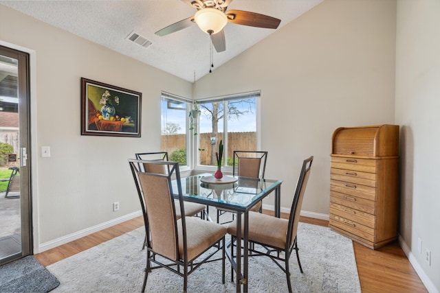 dining room featuring lofted ceiling, a textured ceiling, ceiling fan, and light hardwood / wood-style flooring