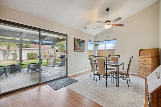 dining area featuring vaulted ceiling, ceiling fan, hardwood / wood-style floors, and a textured ceiling