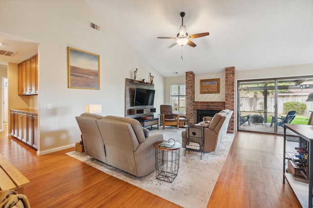 living room featuring a healthy amount of sunlight, a brick fireplace, and light hardwood / wood-style flooring