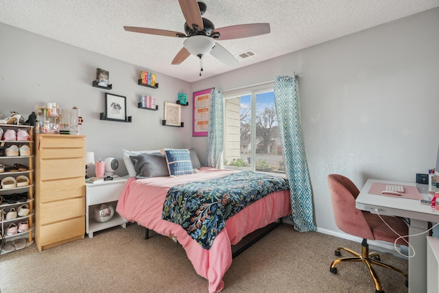 carpeted bedroom featuring ceiling fan and a textured ceiling