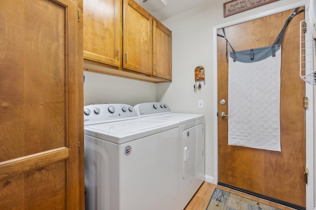 washroom featuring cabinets, washing machine and clothes dryer, and light hardwood / wood-style floors