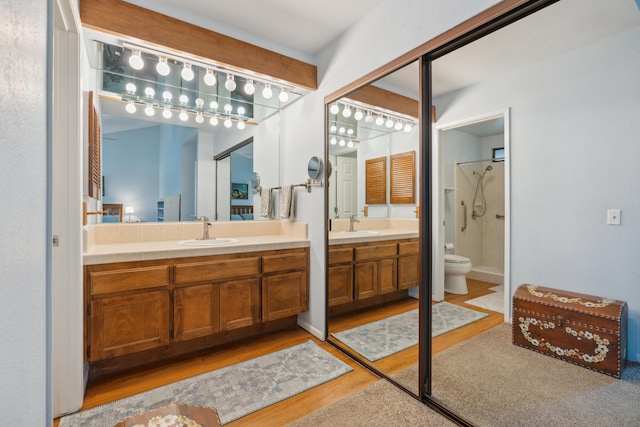 bathroom with walk in shower, hardwood / wood-style floors, vanity, and toilet