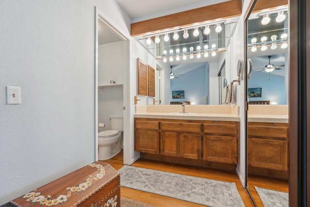 bathroom featuring wood-type flooring, vanity, ceiling fan, and toilet