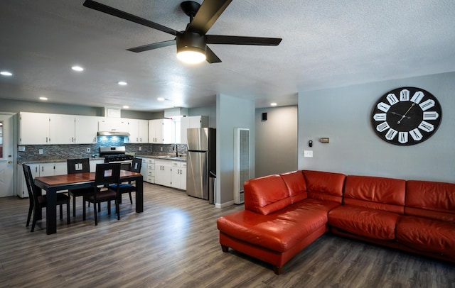 living room with ceiling fan, dark hardwood / wood-style floors, sink, and a textured ceiling