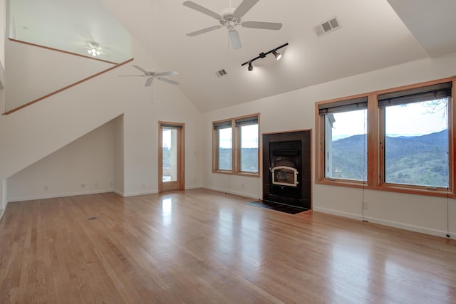 unfurnished living room with light wood-type flooring, visible vents, a mountain view, and lofted ceiling