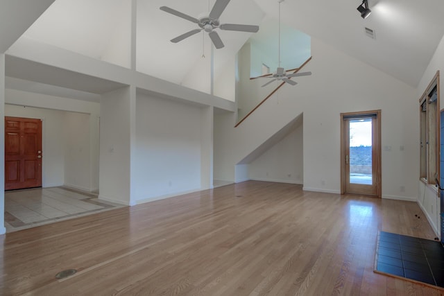 unfurnished living room featuring baseboards, visible vents, a ceiling fan, light wood-style flooring, and high vaulted ceiling