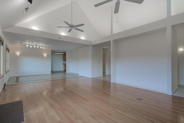 spare room with high vaulted ceiling, a ceiling fan, visible vents, baseboards, and light wood finished floors