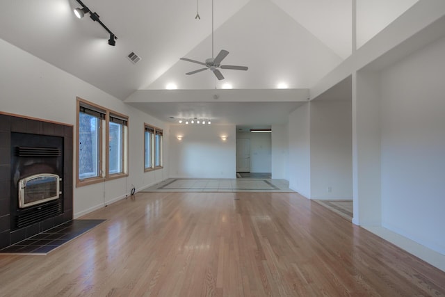 unfurnished living room featuring ceiling fan, a fireplace, wood finished floors, visible vents, and track lighting