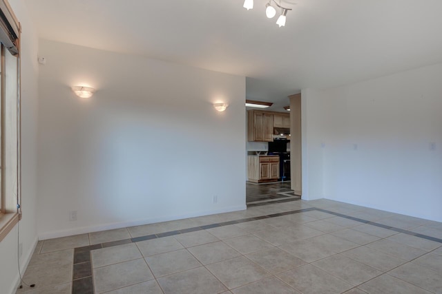 spare room with light tile patterned floors and baseboards