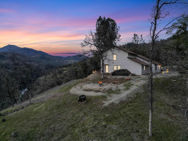 exterior space featuring a yard, a mountain view, and stucco siding