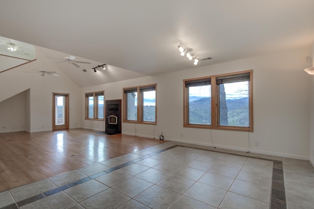 unfurnished living room with vaulted ceiling, light tile patterned flooring, baseboards, and track lighting