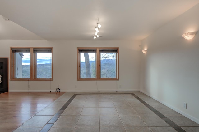 spare room with plenty of natural light, light tile patterned flooring, and baseboards