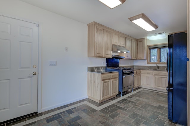 kitchen featuring freestanding refrigerator, light brown cabinets, high end stove, under cabinet range hood, and baseboards